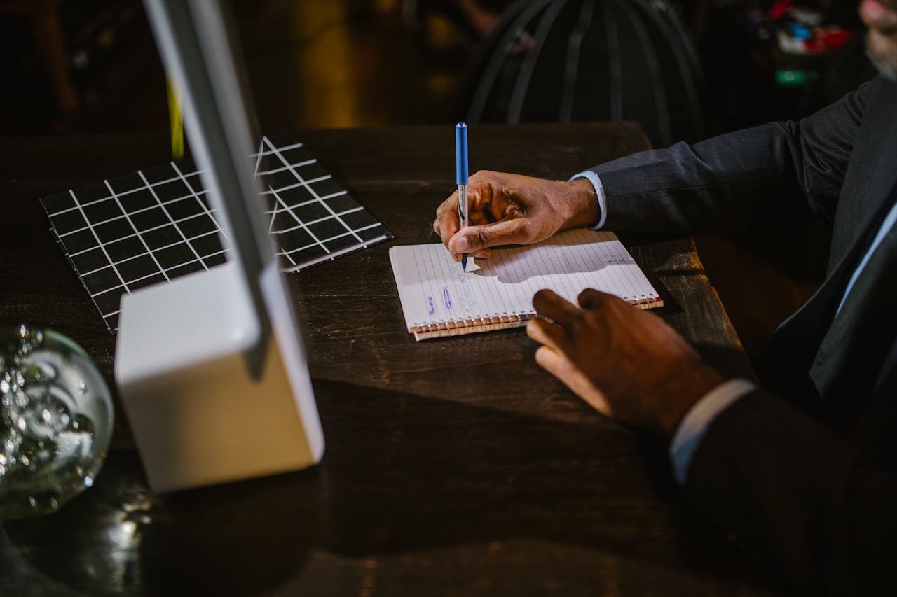 Crafting Captivating Headlines: Your awesome post title goes here A businessman in a suit writing notes on a notebook at a desk, suggesting a professional office environment.